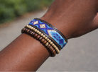 Close-up of a wrist wearing two beaded bracelets with a blurred background
