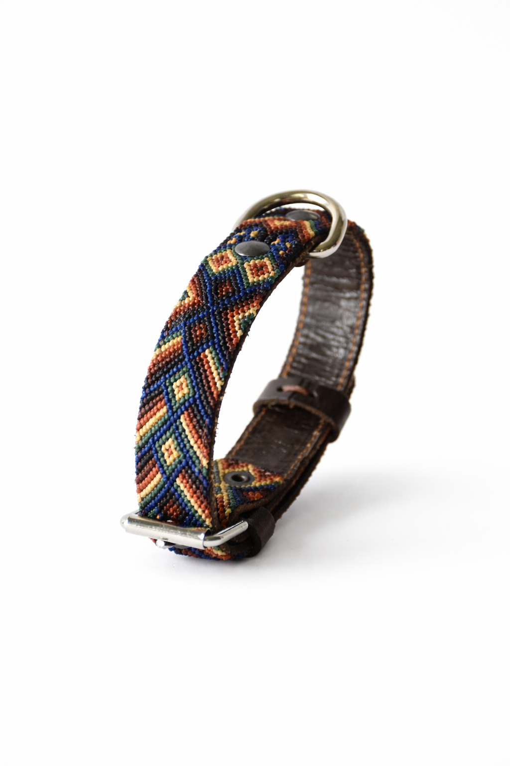 A woven leather dog collar with a colorful geometric pattern in blue, red, orange, and yellow, featuring a brown leather strap and silver-tone metal hardware.