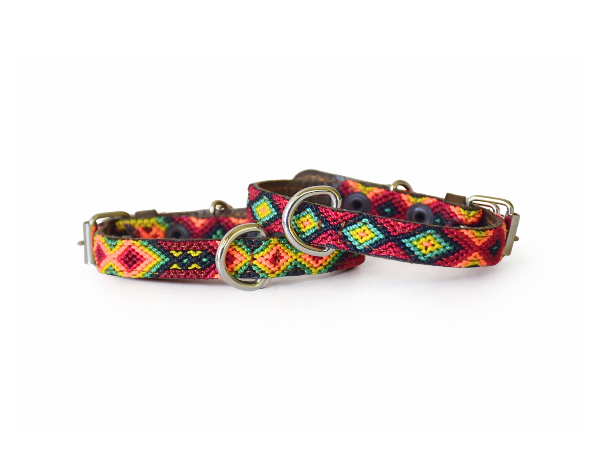 A woven dog collar with a colorful geometric pattern in red, yellow, green, and blue, featuring silver metal rings and a buckle, shown on a plain white background.